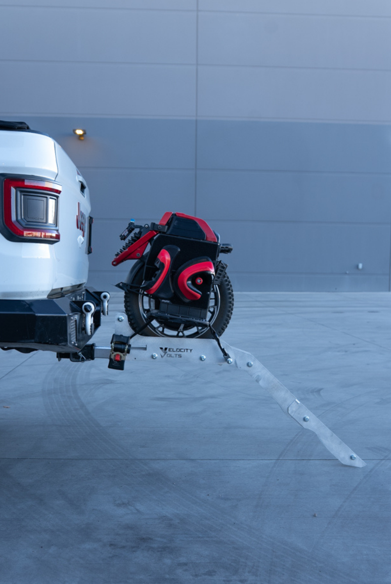 Hitch-mounted EUC rack on a Jeep with the aluminum loading ramp angled down to the pavement