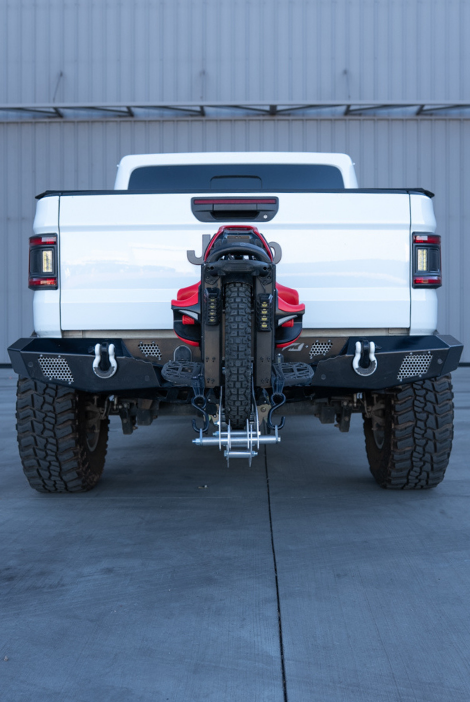 Rear view of a lifted Jeep Gladiator carrying an electric unicycle on a 2-inch hitch carrier