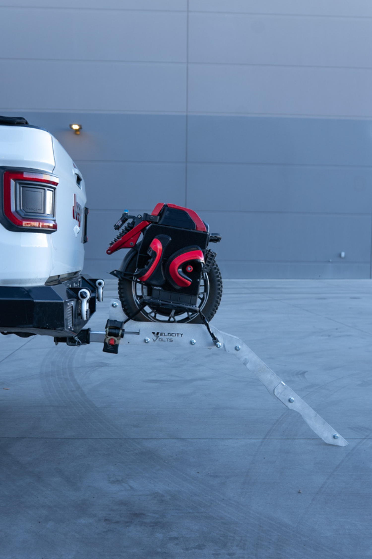 Hitch-mounted EUC rack on a Jeep with the aluminum loading ramp angled down to the pavement