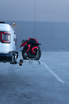 Hitch-mounted EUC rack on a Jeep with the aluminum loading ramp angled down to the pavement
