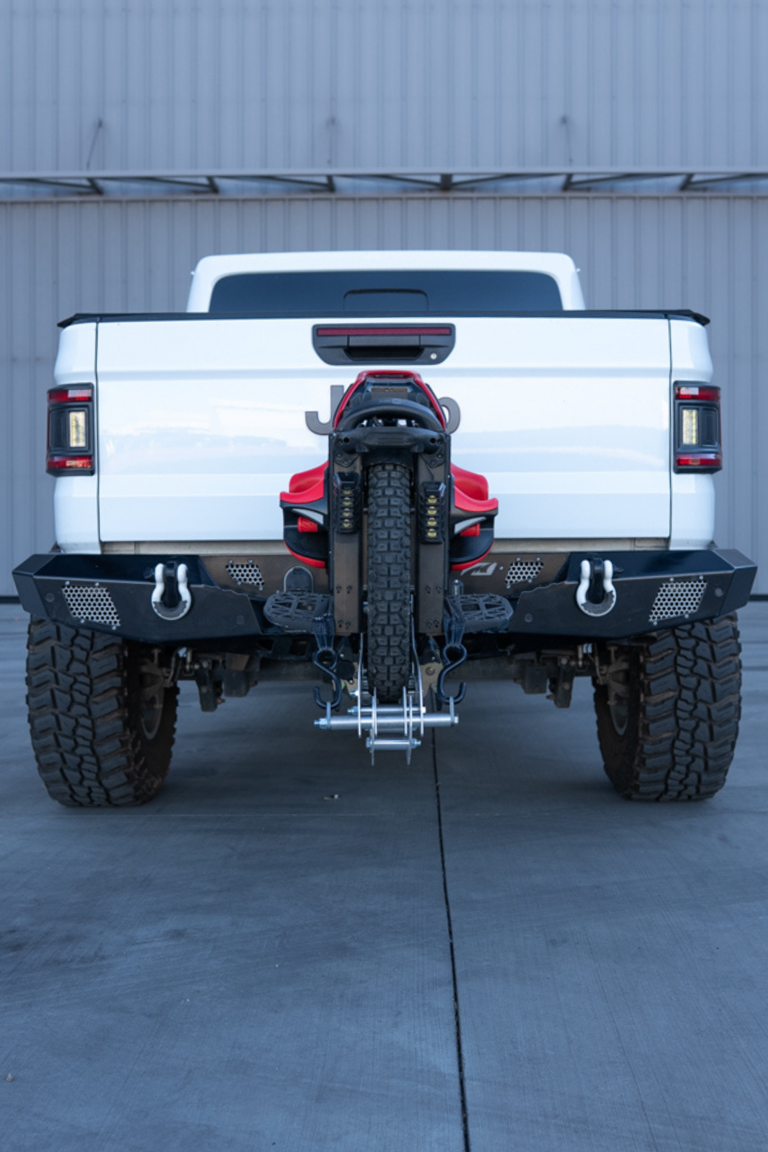 Rear view of a lifted Jeep Gladiator carrying an electric unicycle on a 2-inch hitch carrier
