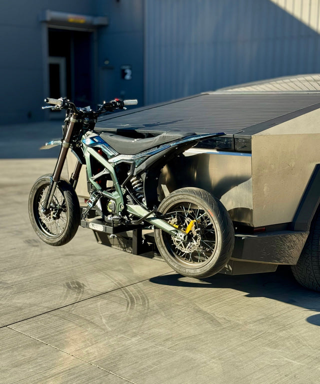 Electric Motorcycle attached to a Tesla Cyber truck in front of an airplane hanger