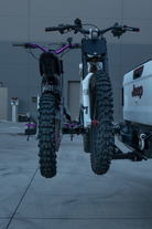 Dual e-moto hitch rack hauling two Surron Ultra Bee electric motorcycles on a 2-inch hitch